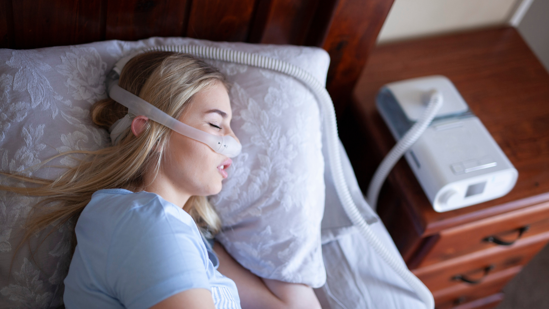 woman sleeping with CPAP machine to prevent sleep apnea which can cause heart problems in some people. woman sleeping with CPAP machine to prevent sleep apnea which can cause heart problems in some people.
