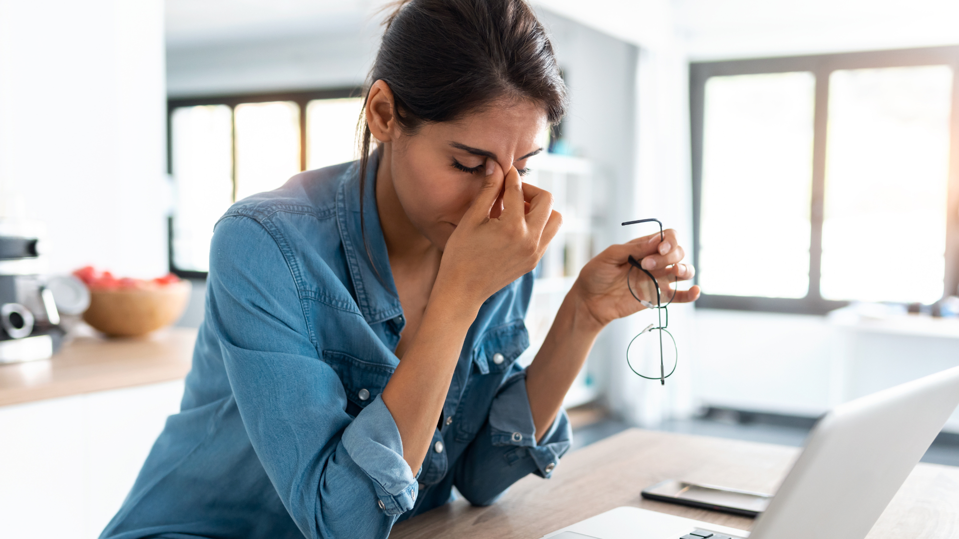 Too much stress and lack of sleep can contribute to chronic disease like breast cancer. Image of stressed business woman working from home on laptop looking worried, tired and overwhelmed.