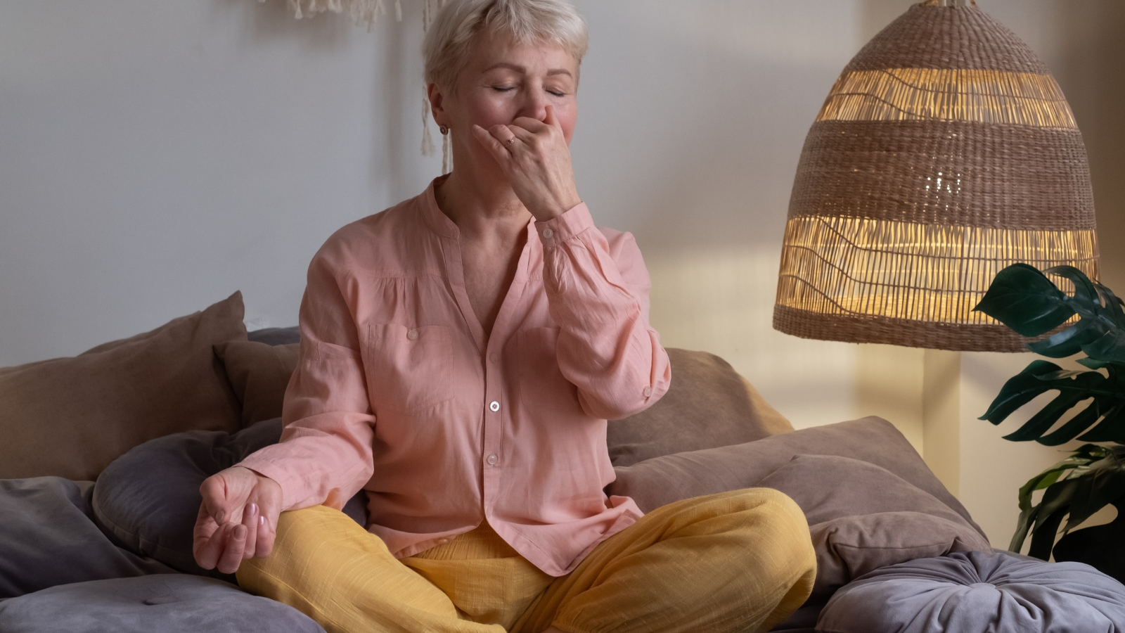 How to practice breathing for it's calming effects and to counteract anxiety Senior woman practicing yoga at home, making Alternate Nostril Breathing exercise, nadi shodhana pranayama to overcome anxiety depression brought by perfectionism