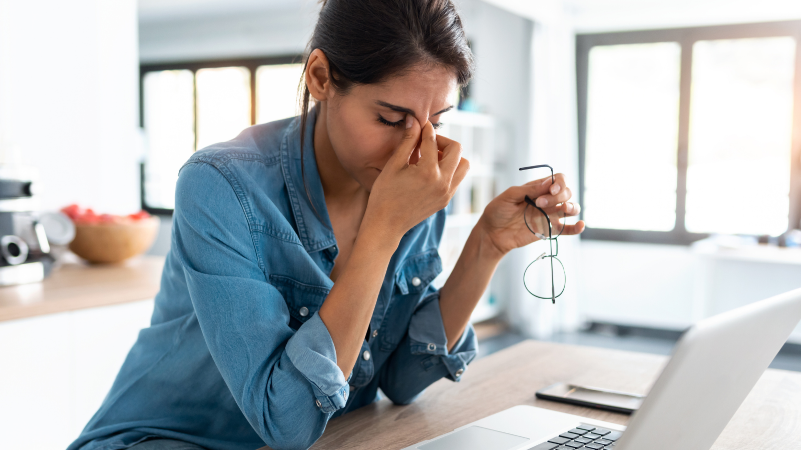 Too much stress can have a negative effect on your quality of sleep and overall health. A stressed business woman working from home on laptop looking worried, tired and overwhelmed.