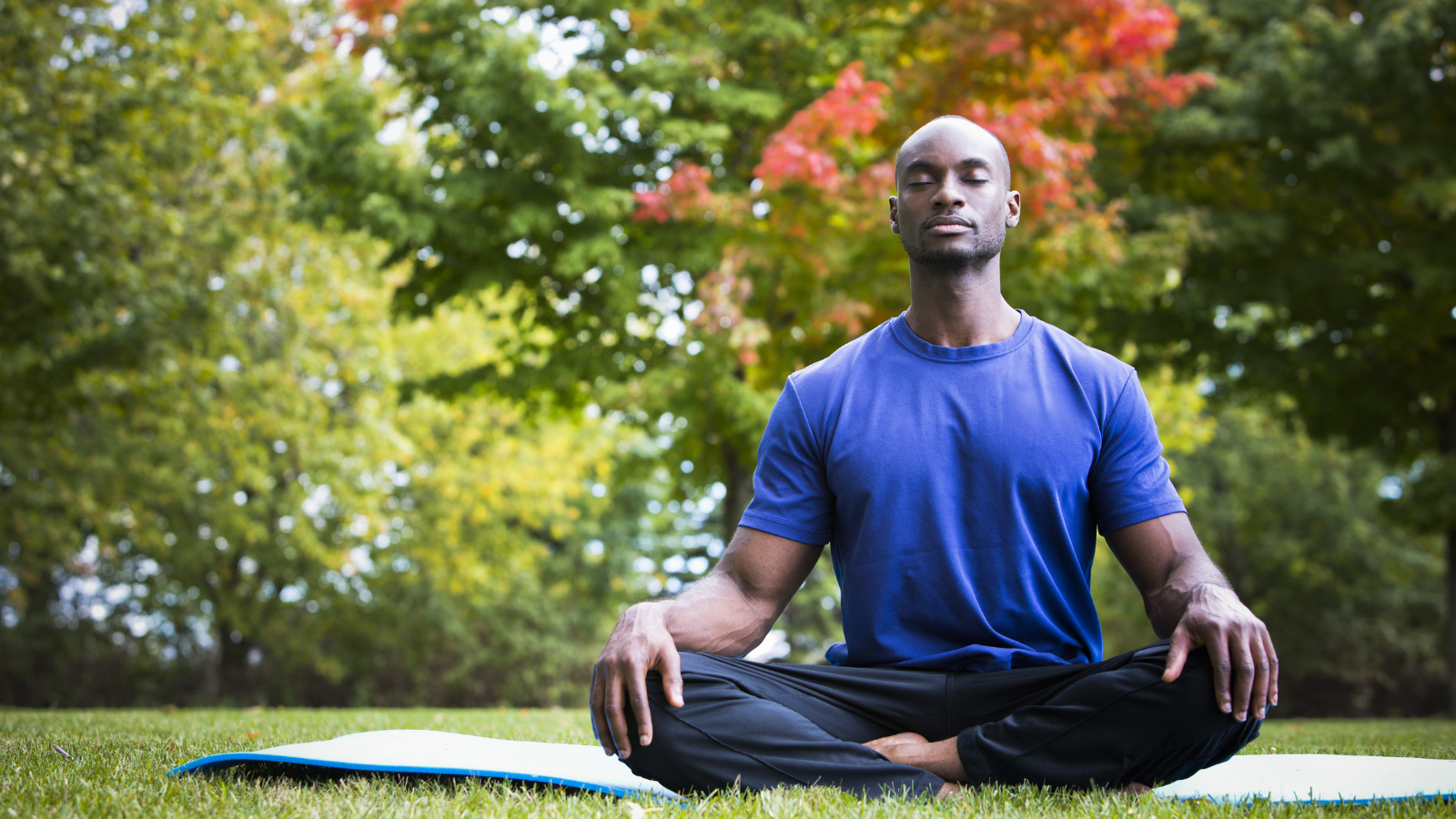 How to live life in balance with rest for resilience young black man wearing athletic wear sitting in the park doing yoga meditation, a somatic approach to exercise