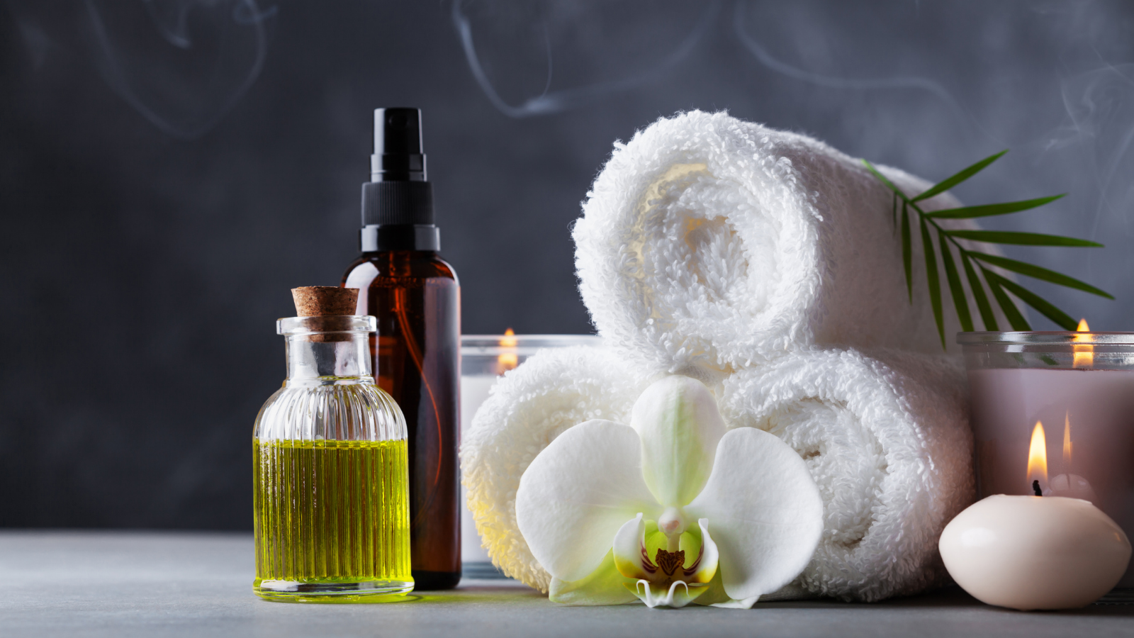 Self-care can be a great way to settle mind and body for a good night's sleep. Aromatherapy, spa, beauty treatment and wellness background with massage oil, orchid flowers, towels, and candles.