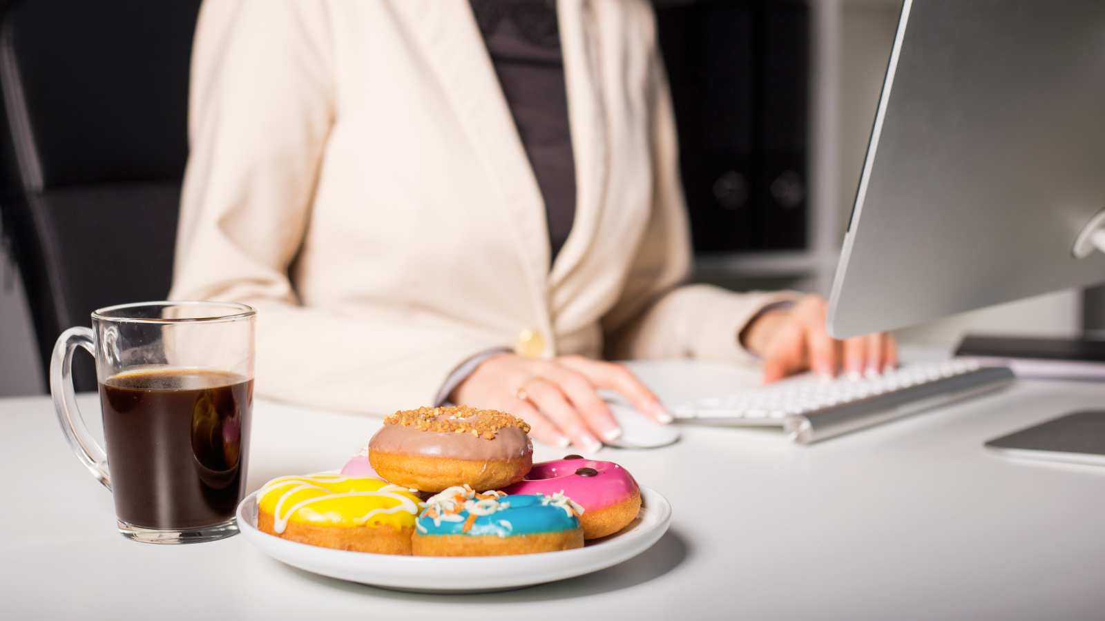 Image of woman working with coffee nearby can also be an issue when it comes to a good night's sleep. Woman having coffee and donuts at work.