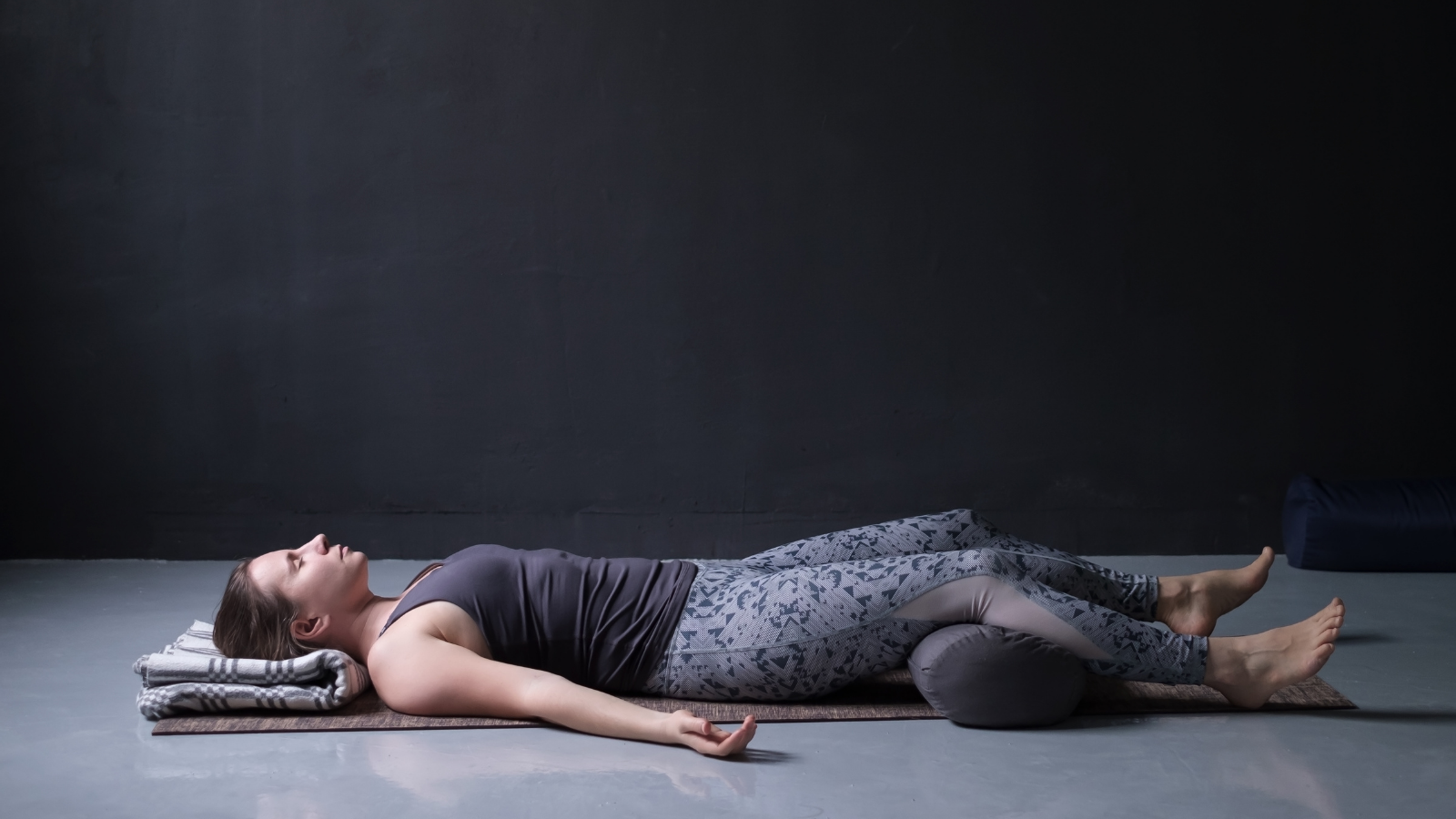 How to practice yoga's foundational pose for beginners and everyone Young woman practicing yoga's Savasana or Corpse Pose.