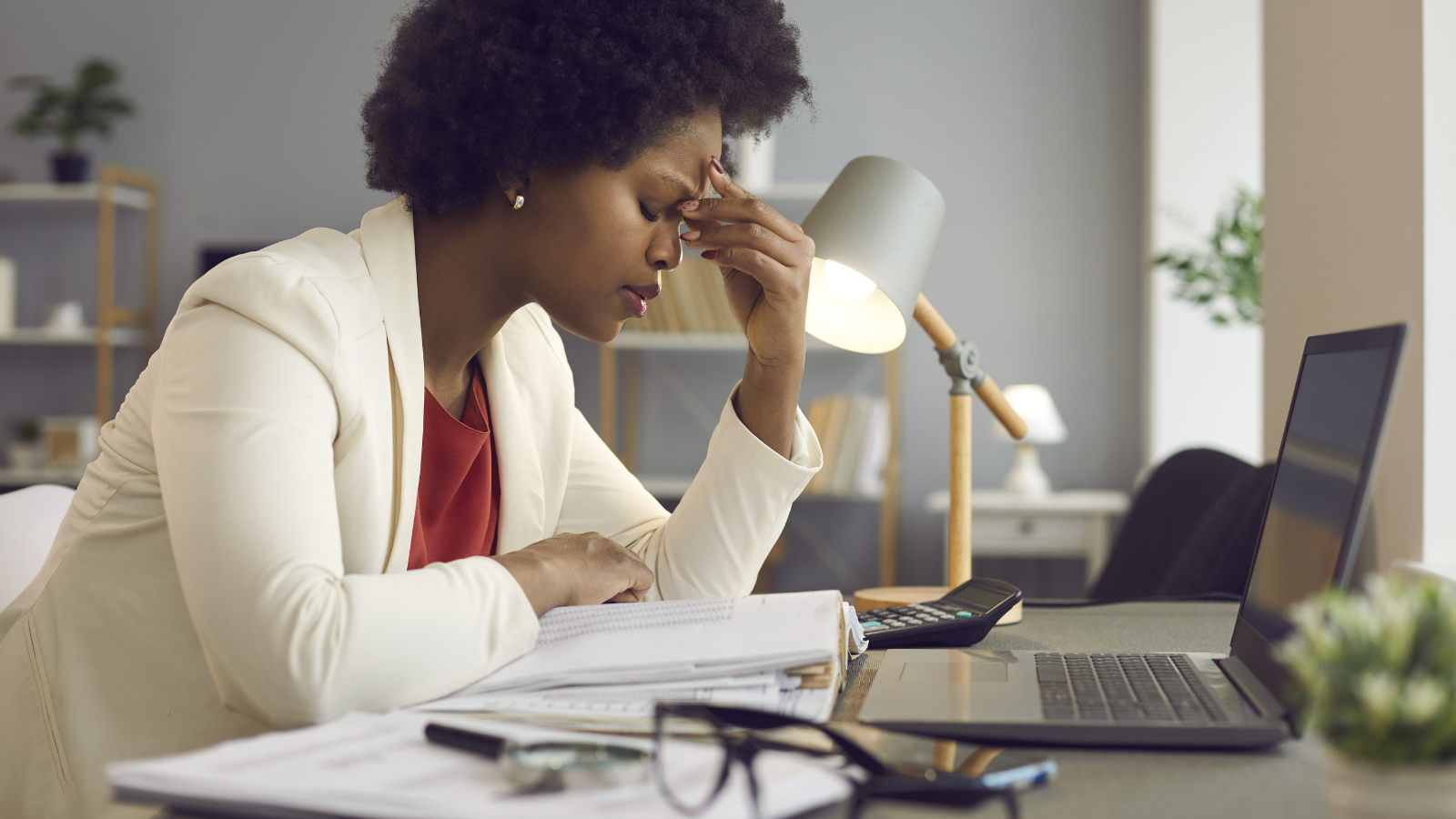 Frustrated young african american woman keeping eyes closed and massaging nose after working at laptop for long time in office Feeling tired and stressed, workload, burnout and fatigue